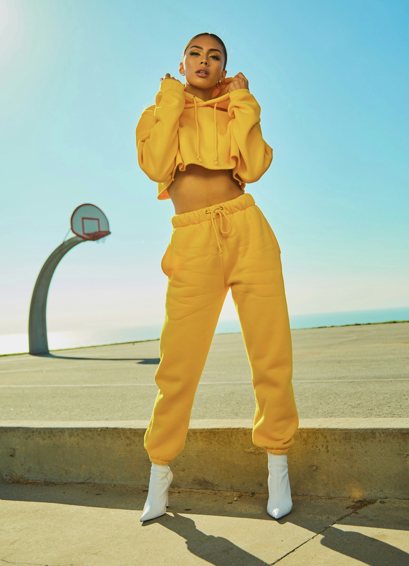 Woman wearing a yellow outfit and white trainers on an outdoor court