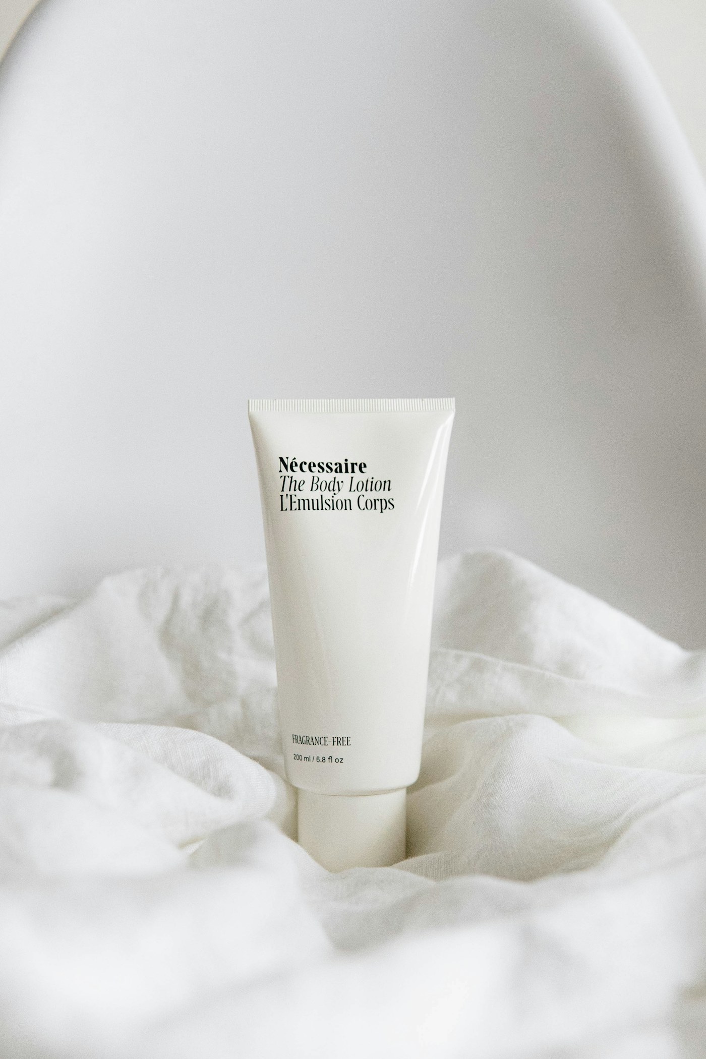 Skincare tube resting on soft white bedding