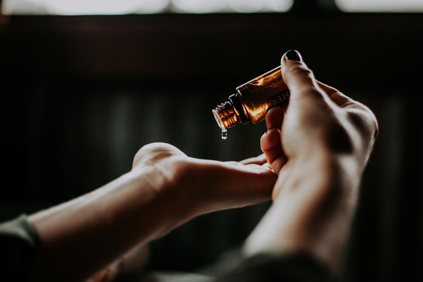 Hands holding a perfume bottle in a softly lit room