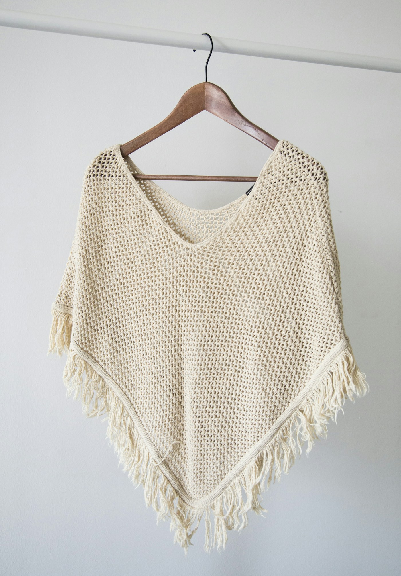 Light knitted top hanging against a pale wall