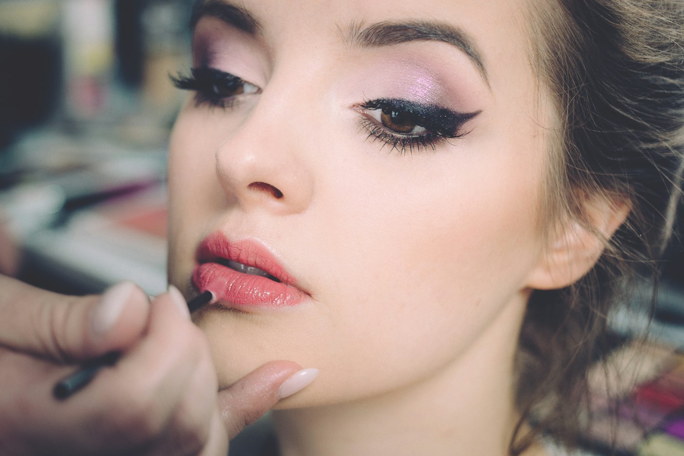 A makeup brush being used to apply colour to lips